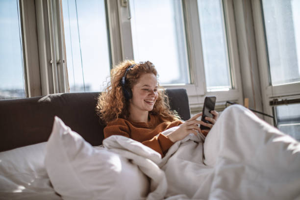 istock Young woman using a mobile phone in bed 1201432788