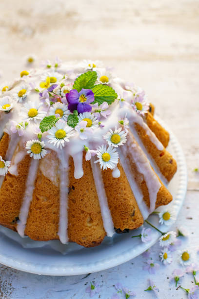 istock Easter yeast cake (Babka) covered with icing and decorated with edible flowers on a white plate on a white wooden table. 1201433675
