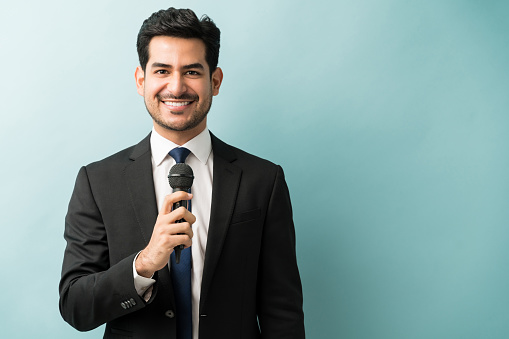 Handsome and successful business professional holding microphone at studio