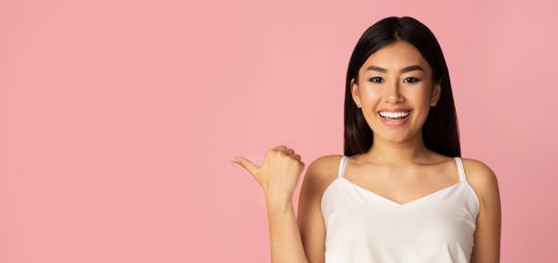 istock Charming asian girl pointing fingers aside at free space 1201438183