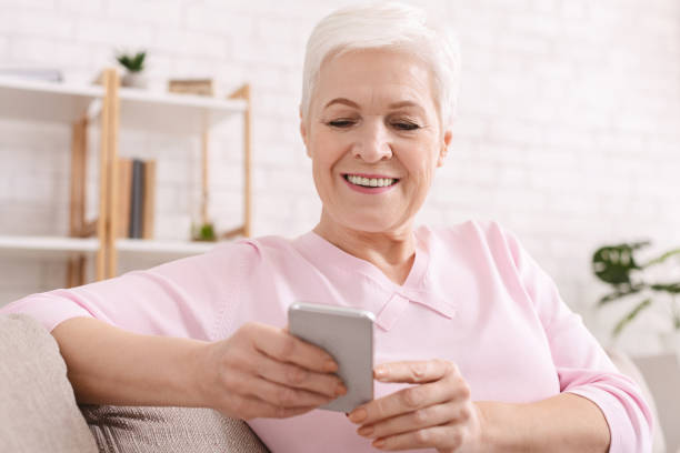 istock Cheerful senior lady enjoying modern cellphone at home 1201438205