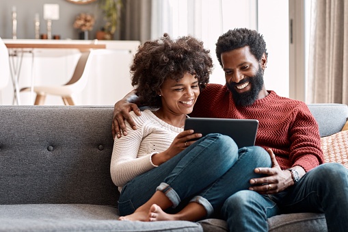 Shot of an affectionate couple using a digital tablet while relaxing on the sofa at home