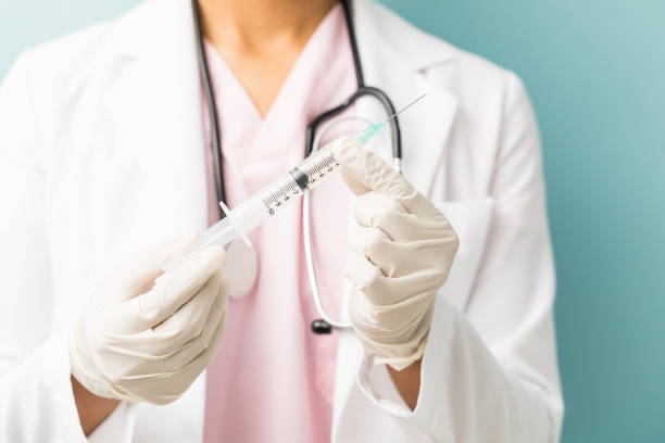 istock Doctor Wearing Gloves With Syringe In Studio 1201441022