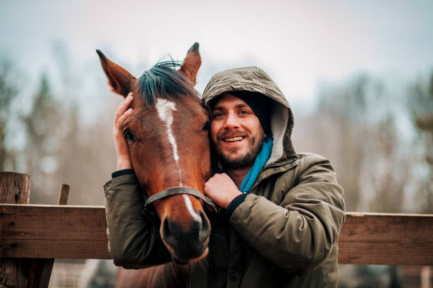 istock Young man hugs a horse. Autumn outdoors scene 1201443364