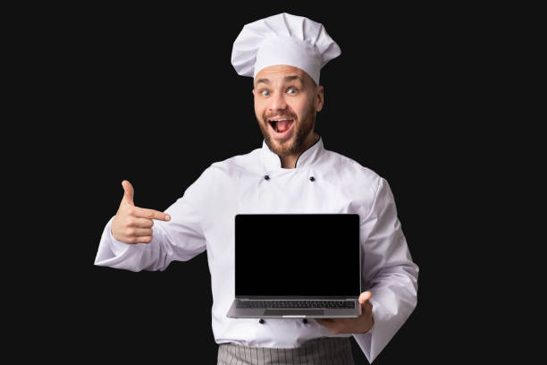 istock Cook Man Showing Laptop Empty Screen Gesturing Thumbs-Up, Black Background 1201445729