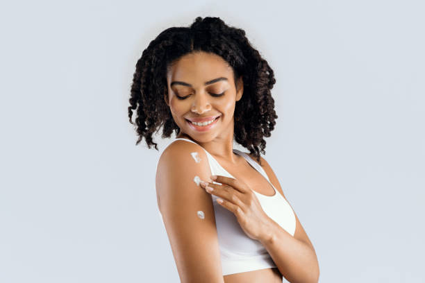 istock Pretty smiling girl applying cream on her shoulder 1201445763