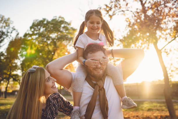 istock Playful daughter covering father's eyes while sitting on his shoulders 1201446387