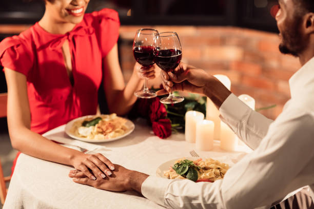 istock Unrecognizable Afro Lovers Clinking Glasses Holding Hands In Restaurant, Cropped 1201446821