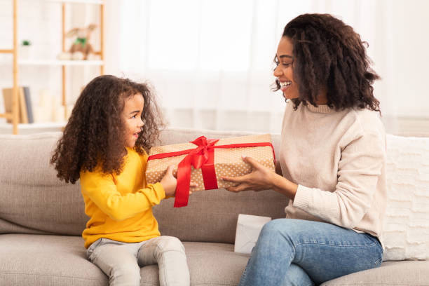 istock African American Mom Giving Gift To Daughter Sitting On Couch 1201449708