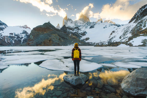 Woman standing and looking at Fitz Roy mountain in Patagonia Young Caucasian woman standing and looking at Fitz Roy mountain in Patagonia chile tourist stock pictures, royalty-free photos & images
