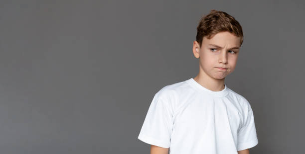 istock Teen boy looking aside with doubtful expression 1201449932