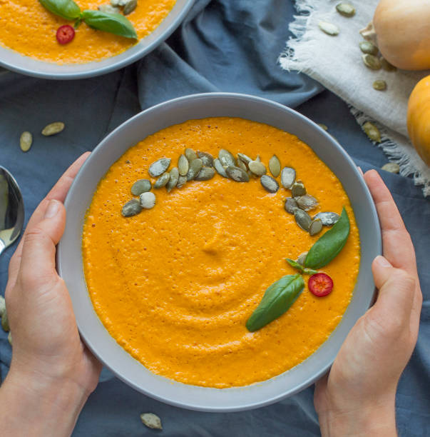 istock Hands Holding plate with vegan pumpkin cream soup 1201450302