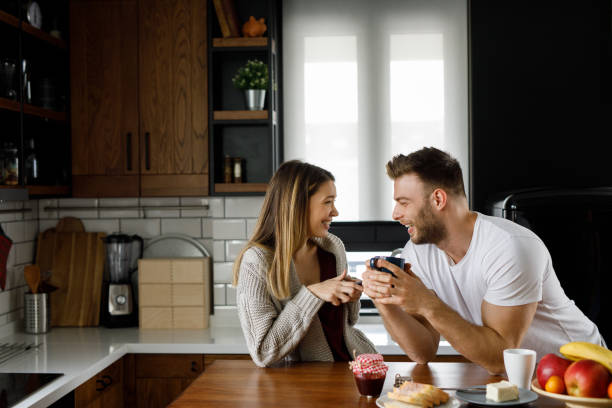 istock Young affectionate couple looking at mobile phone in the kitchen 1201452763