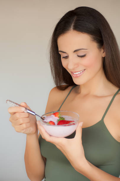 istock Serene young girl eating strawberries with yogurt 1201453584