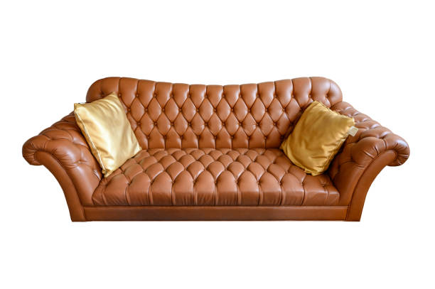 istock Orange vintage leather sofa buttoned with golden pillows. Isolated on background 1201453648
