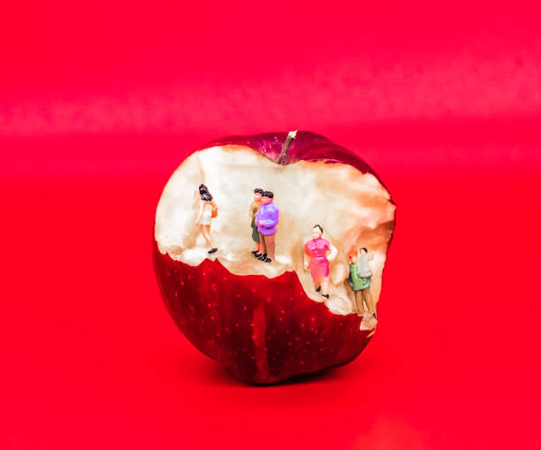 Miniature people ascending a bitten apple that looks kind of like an escalator. Anthropomorphic scene with food and fake people in daily life
