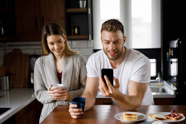istock Boyfriend using smart phone with upset girlfriend standing beside 1201455298