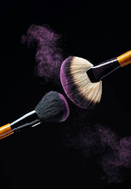 istock Makeup concept with a  professional makeup brushes with glowing purple eye shadow isolated on black background. 1201455379