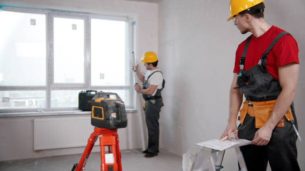 istock Two men workers measuring the distance from the windowsill to the ceiling and another writing notes about it 1201456062