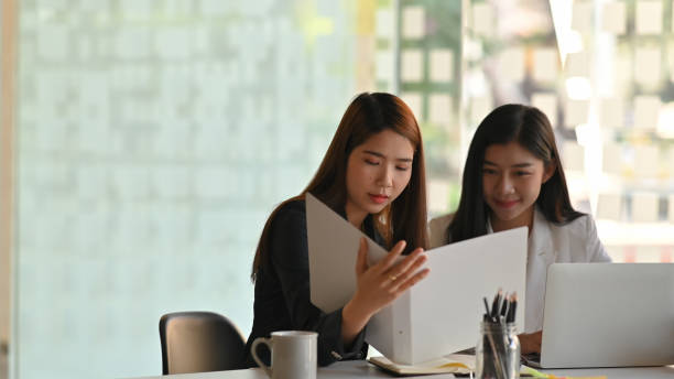 istock Beautiful business women while talking/discussing about work at the modern office. 1201457441