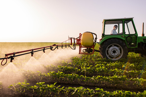 Tractor pulverizando pesticidas en el campo de soja con pulverizador en primavera photo