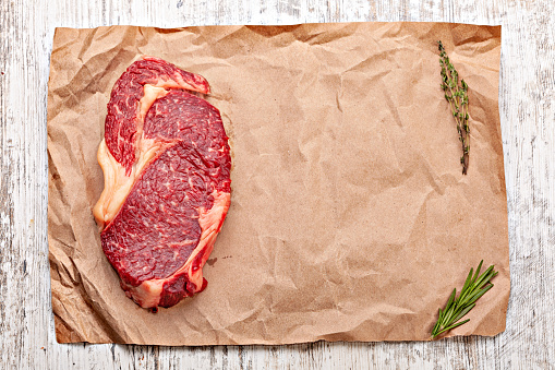 Raw beef steak on brown paper. Top view. Flat lay. Copy space.