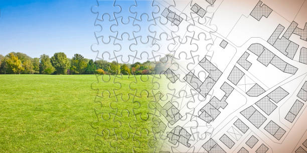 Planning a new city - concept image in jigsaw puzzle shape with an imaginary cadastral map of territory with buildings, fields and roads against a green area