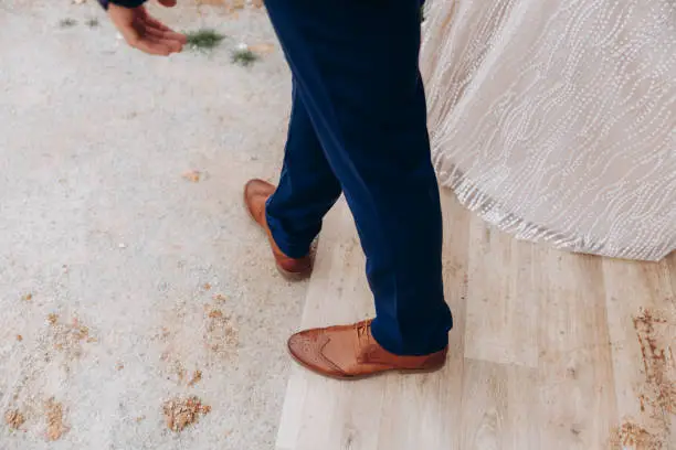 Groom legs in brown classic boots walking with bride.