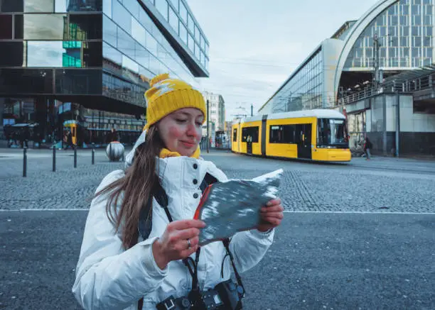 Young lady travels with tourist city map on hoiliday in Berlin, Germany, in winter.