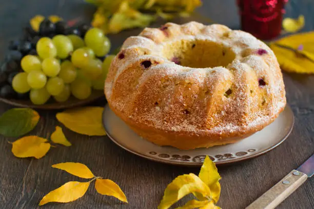 Homemade bundtcake with autumn grapes on a table with fall decoration