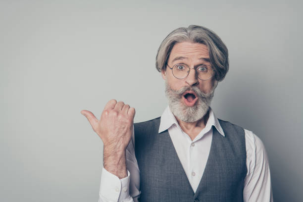 istock Look incredible discounts. Astonished crazy impressed old man indicate ads promotion point forefinger copyspace scream wow omg suggest select wear shirt isolated over grey color background 1201467640
