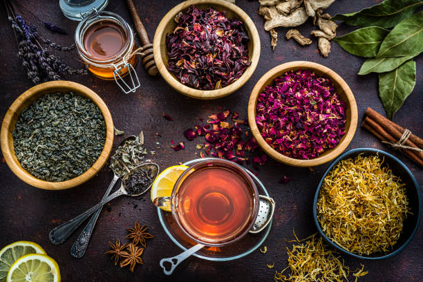 istock Tea cup with various dried tea leaves and flowers shot from above on brown table 1201469827