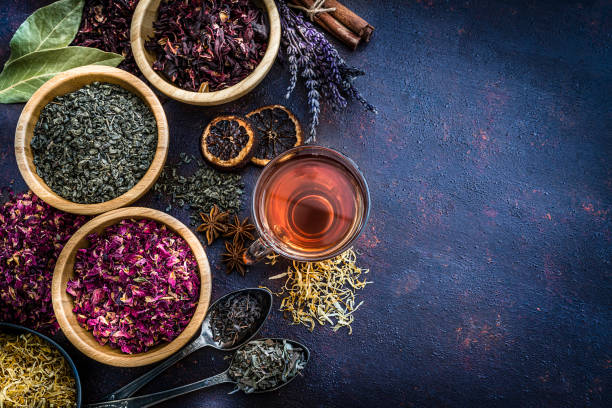 istock Various dried tea leaves and flowers with a tea cup shot from above on abstract background. Copy space 1201470025