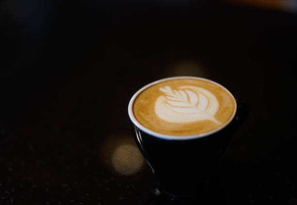 istock latte art in a black glass on the table Black background 1201473178