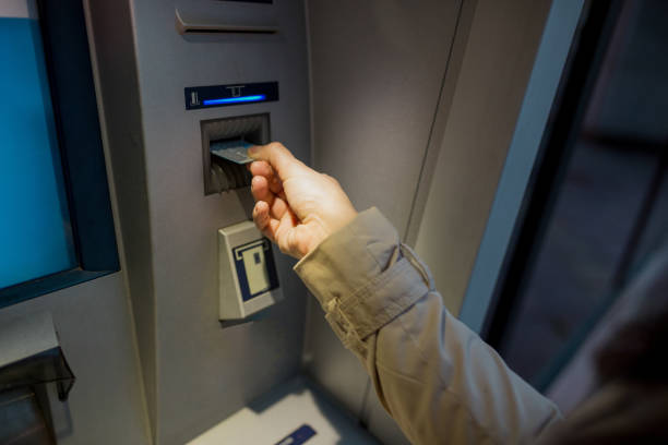 istock young woman inserting a credit card to ATM 1201473442