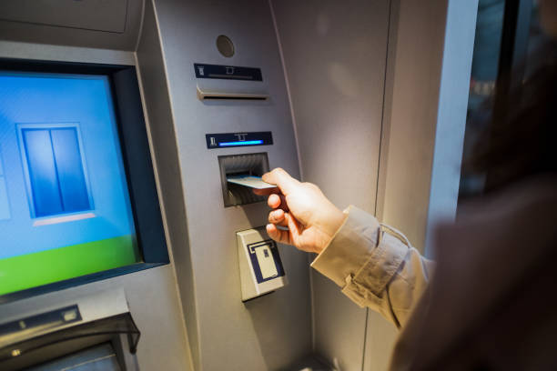 istock young woman inserting a credit card to ATM 1201473481
