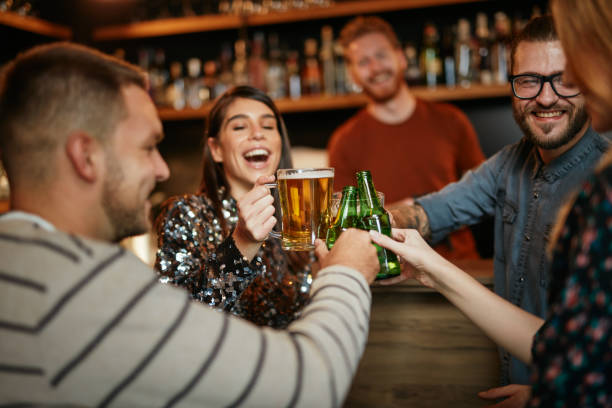 amici in piedi al bar e che brindano con la birra. - irish culture beer drinking pub foto e immagini stock