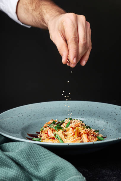 istock Chef hands cooking pasta and adding herbs and pepper on dark background 1201473711