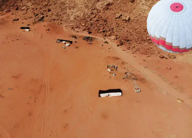 Aerial view of the desert Wadi Rum with a floating hot air balloon, rocks, and sand