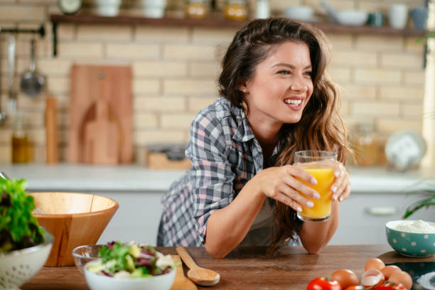 istock Young woman drinking orange juice in kitchen 1201482050