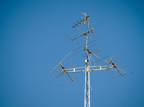 Old television antenna signal transmission on sky blue. Old technology TV communication.
