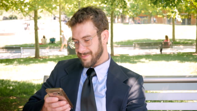 Happy smiling business man reading emails or social media posts on smart phone
