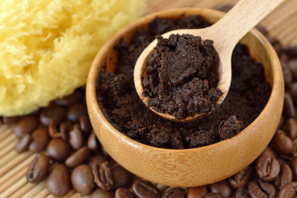 Homemade coffee scrub face mask in wooden bowl with spoon on coffee beans stock photo