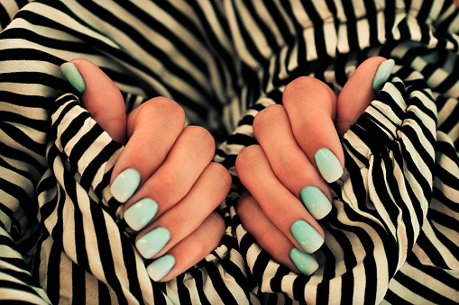 Cierra la mano con una manicura de uñas de color azul degradado sobre una tira de fondo. photo