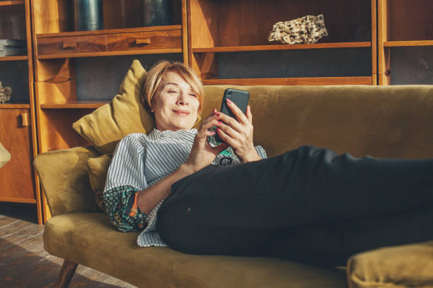 istock Senior lady with smart phone resting at home 1201486154