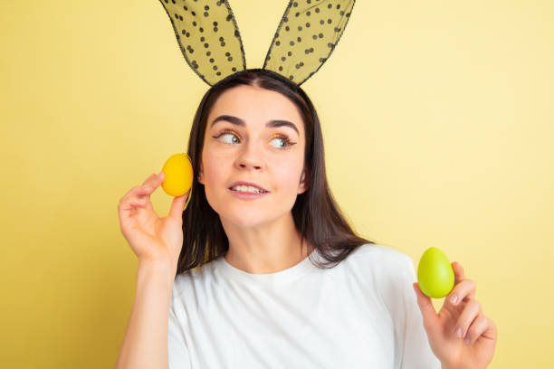 femme de lapin de pâques avec des émotions lumineuses sur le fond jaune de studio - easter rabbit bizarre women photos et images de collection