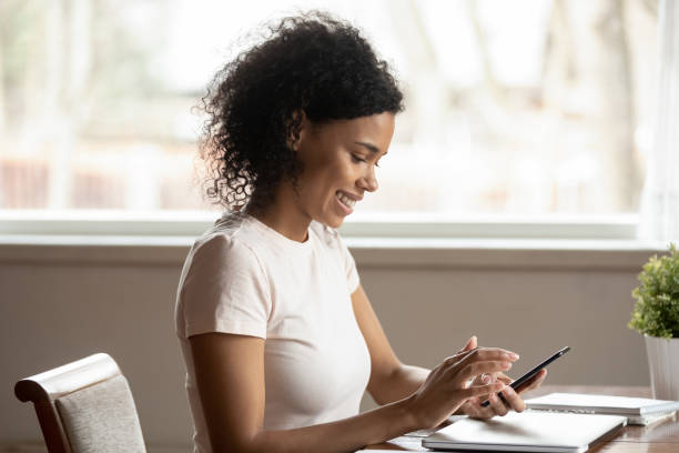 istock Smiling biracial woman using modern cellphone texting 1201492874