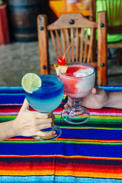 A man and a woman with multi-colored cocktails in their hands in restaurant Mexico
