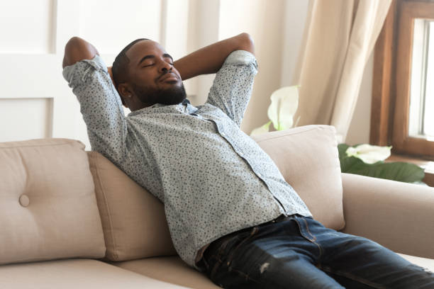 istock Calm african American relaxing on comfortable sofa at home 1201494885
