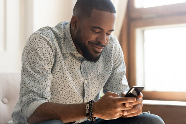 istock Smiling african American man feel happy texting on smartphone 1201494903